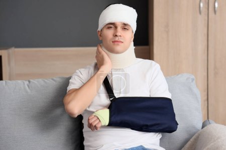 Injured young man after accident sitting on sofa at home