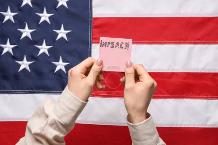 Mujer sosteniendo un pedazo de papel con la palabra IMPEACH contra la bandera de EE.UU.