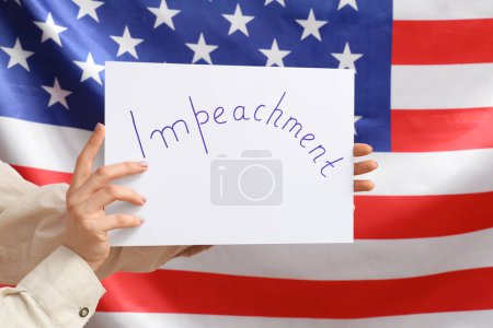 Affiche de piquet IMPEACHMENT tenue par une femme sur fond de drapeau américain
