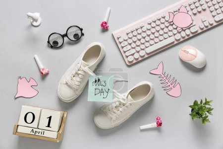 Foto de Zapatos con cordones atados, teclado de ordenador y calendario sobre fondo blanco. Broma del Día de los Inocentes - Imagen libre de derechos