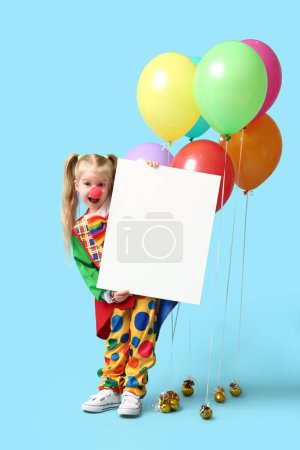 Foto de Chica divertida en traje de payaso con cartel en blanco y globos sobre fondo azul - Imagen libre de derechos
