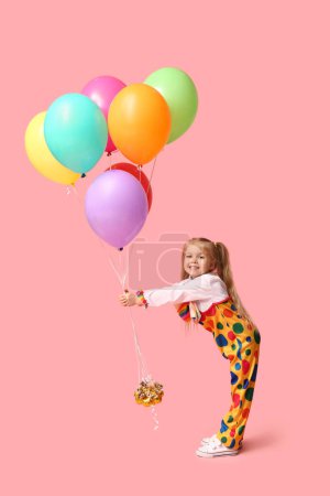 Foto de Niña sonriente en traje de payaso con globos sobre fondo rosa - Imagen libre de derechos