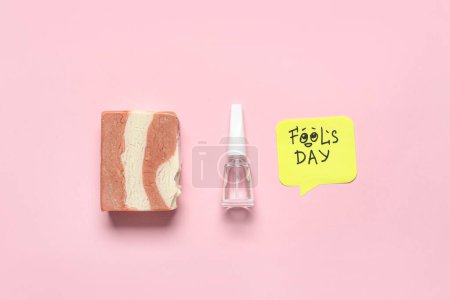 Foto de Esmalte de uñas, jabón y nota adhesiva sobre fondo rosa. Broma del Día de los Inocentes - Imagen libre de derechos
