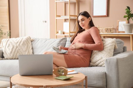 Young pregnant woman with money sitting on sofa at home. Maternity Benefit concept