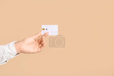 Male hand with credit card on beige background