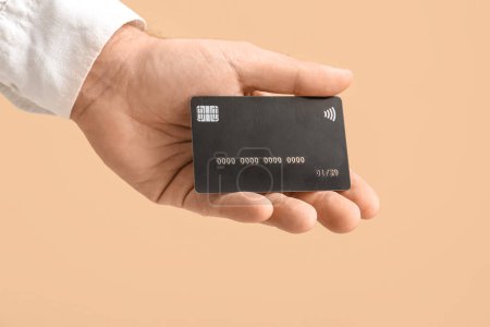 Male hand with credit card on beige background