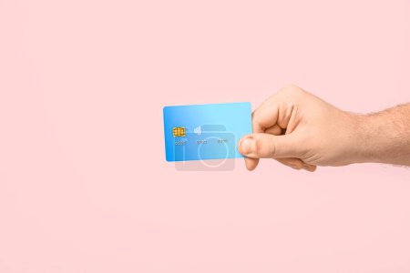 Mano masculina con tarjeta de crédito sobre fondo rosa