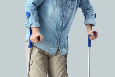 Junger Mann mit Krücken auf hellem Hintergrund. Nationaler Monat des Bewusstseins für Zerebralparese