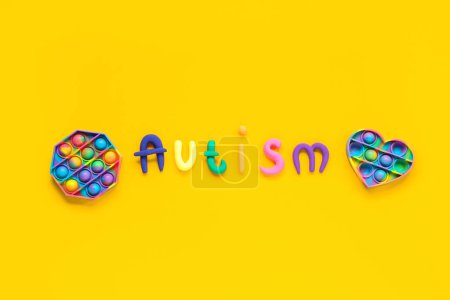 Word AUTISM and pop it on yellow background. Autism disorder concept