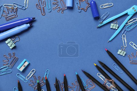 Cadre en feutre, crayons et trombones sur fond bleu. Fin de l'école. Vue du dessus