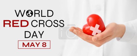 Doctor con el corazón en la mano, primer plano. Banner para el Día Mundial de la Cruz Roja