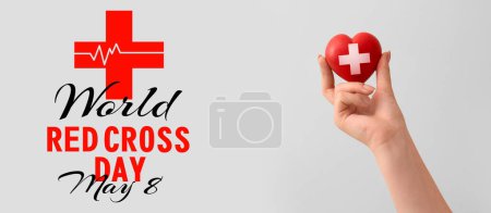 Mano con corazón sobre fondo claro. Banner para el Día Mundial de la Cruz Roja