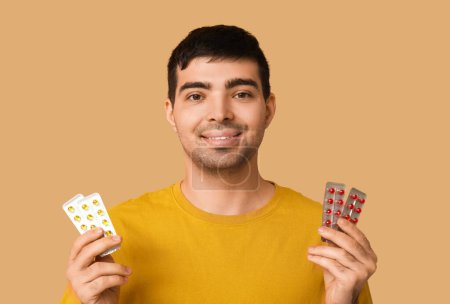 Foto de Hombre joven con ampollas de píldoras de vitamina A sobre fondo beige, primer plano - Imagen libre de derechos