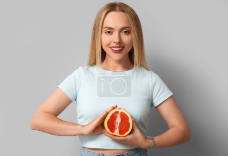 Junge Frau mit Grapefruit auf hellem Hintergrund