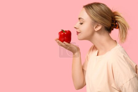 Young woman with bell pepper on pink background