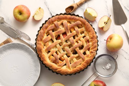 Baking dish with tasty homemade apple pie, fruits and cutlery on white grunge background
