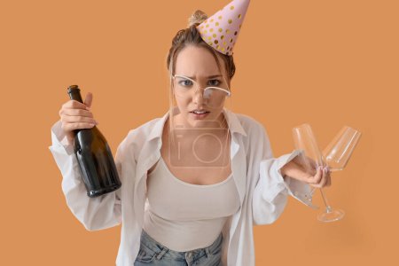 Foto de Joven mujer de negocios con resaca y champán después de la fiesta de cumpleaños sobre fondo beige - Imagen libre de derechos