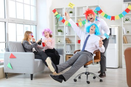 Foto de Compañeros de negocios en pelucas celebrando el Día de los Inocentes en la fiesta de oficina - Imagen libre de derechos