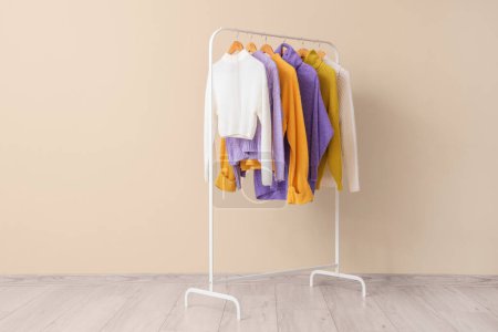 Photo for Rack of stylish clothes near beige wall - Royalty Free Image