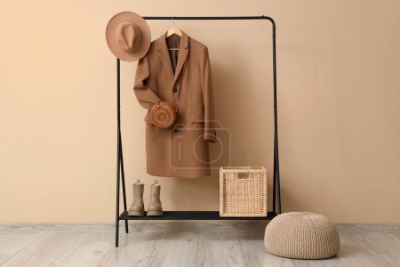 Photo for Rack with organized set of clothes near beige wall - Royalty Free Image