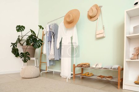 Photo for Interior of light room with rack of stylish clothes, houseplant and shelf with shoes - Royalty Free Image