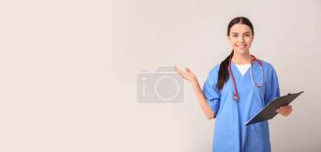 Female nurse showing something on light background with space for text