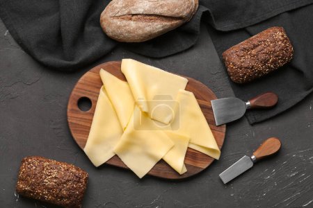 Tafel mit leckeren Käsescheiben und Brot auf dunklem Hintergrund