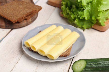 Tasty sandwich with cheese in plate on light wooden background, closeup