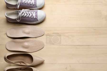 Photo for Pair of orthopedic insoles and stylish female shoes on wooden background - Royalty Free Image