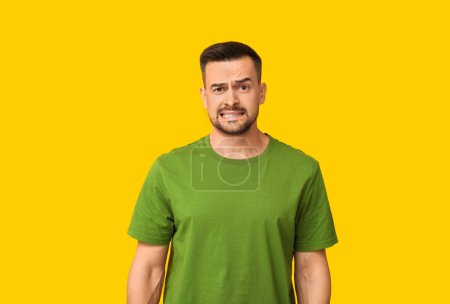 Photo for Handsome ashamed young man on yellow background - Royalty Free Image
