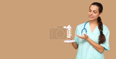 Foto de Retrato de mujer osteópata sosteniendo el modelo de columna vertebral sobre fondo beige con espacio para texto - Imagen libre de derechos