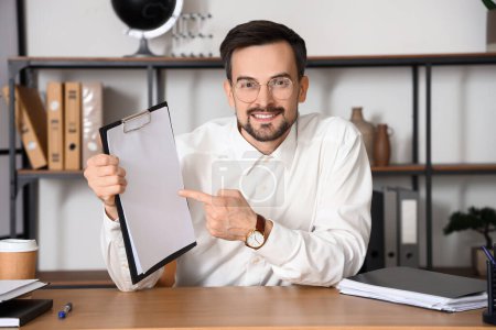 Male tutor pointing at clipboard while giving online lesson in room