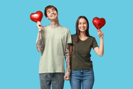 Téléchargez les photos : Jeune couple avec des ballons à air en forme de coeur sur fond bleu - en image libre de droit