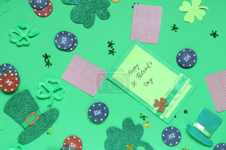 Composition with poker chips, cards, greeting card and decorations for St. Patrick's Day celebration on green background