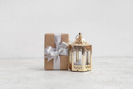 Geschenkkarton mit muslimischer Lampe zum Ramadan auf weißem Tisch