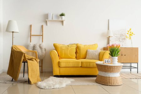 Photo for Interior of light living room with sofa and tulips in vase for International Women's Day - Royalty Free Image