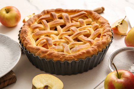 Backform mit leckerem hausgemachten Apfelkuchen, Sieb und Früchten auf weißem Grunge-Hintergrund