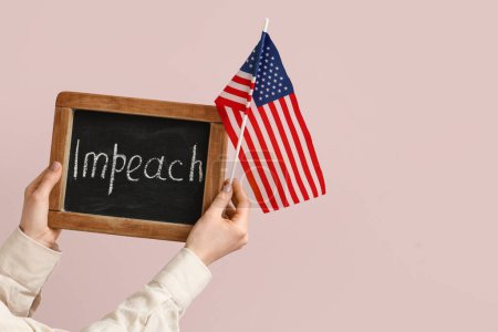 Woman holding chalkboard with word IMPEACH and USA flag on pink background