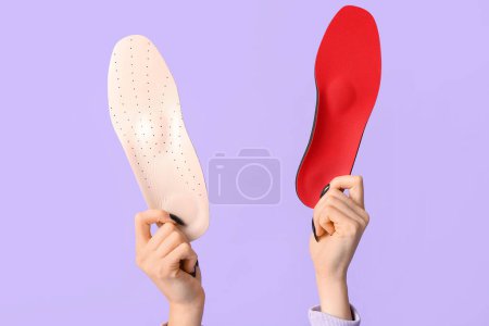 Photo for Female hands holding orthopedic insoles on lilac background - Royalty Free Image