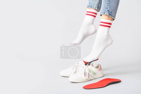 Photo for Female legs, orthopedic insoles and sneakers isolated on white background, closeup - Royalty Free Image