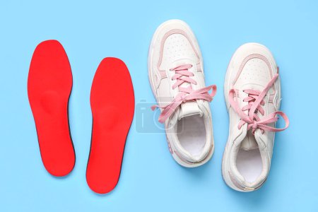 Photo for Sneakers and red orthopedic insoles on blue background - Royalty Free Image