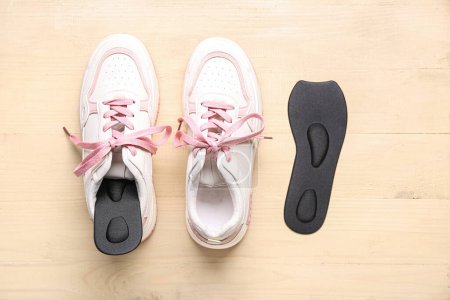 Photo for Sneakers and black orthopedic insoles on beige background - Royalty Free Image