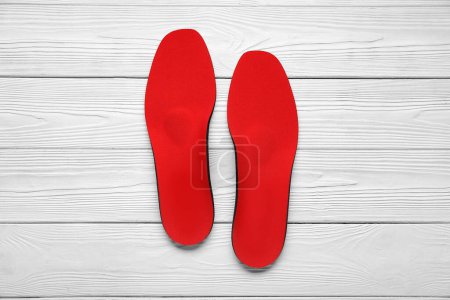 Photo for Red orthopedic insoles on white wooden background - Royalty Free Image
