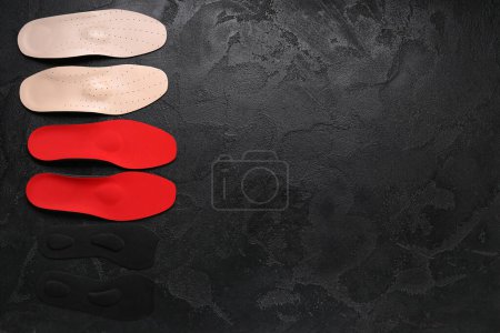 Photo for Two pairs of orthopedic insoles on black grunge background - Royalty Free Image
