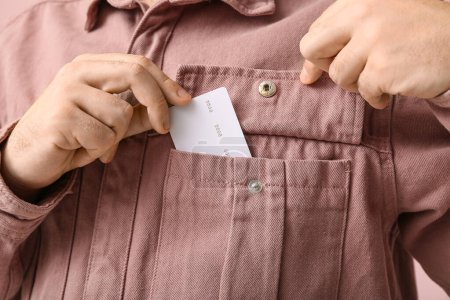 Young man putting credit card in shirt pocket, closeup