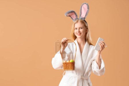 Photo for Young woman in bathrobe with Easter basket and pumice stone on color background - Royalty Free Image