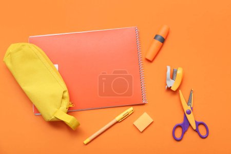 Foto de Cuaderno y estuche de lápiz con papelería sobre fondo naranja. Vista superior - Imagen libre de derechos