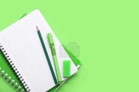 Foto de Cuaderno con lápiz y bolígrafo sobre fondo verde. Vista superior - Imagen libre de derechos