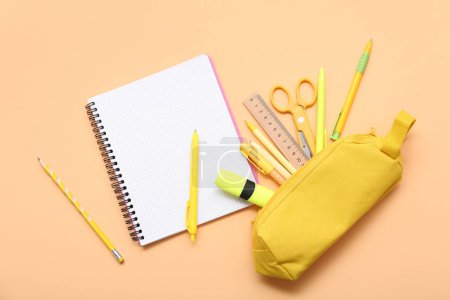 Foto de Cuaderno y estuche de lápiz con papelería sobre fondo beige. Vista superior - Imagen libre de derechos