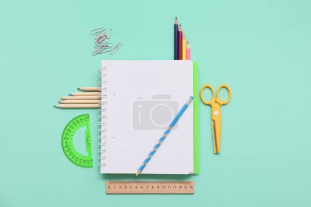 Foto de Cuaderno, lápiz y tijeras sobre fondo turquesa. Vista superior - Imagen libre de derechos